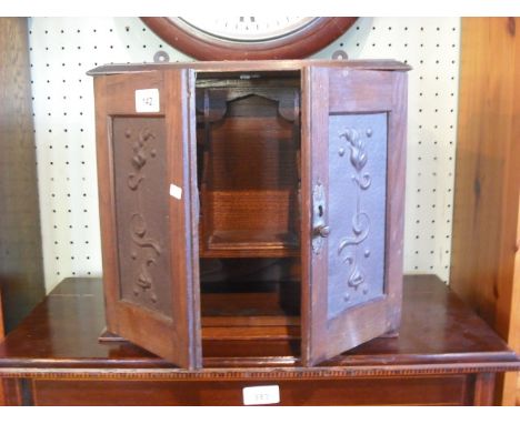 A late 19th century oak humidor cabinet, having a pair of doors, each decorated with a pressed copper panel in the Art Nouvea