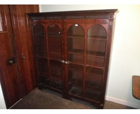 An Edwardian mahogany bookcase, having moulded and fluted cornice over a -pair of glazed doors, enclosing adjustable shelves 