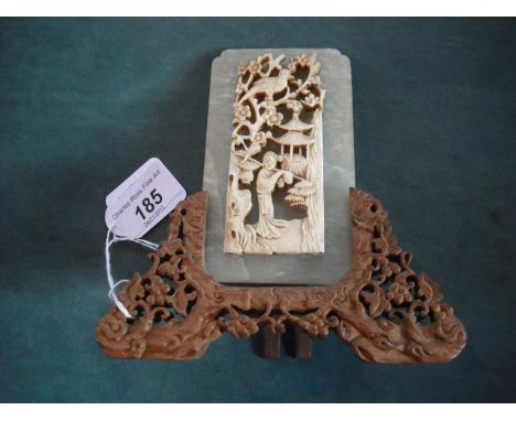 A early 20th century carved Chinese bone plaque of a figure with basket of fruit, in a landscape beside flowering tree with b