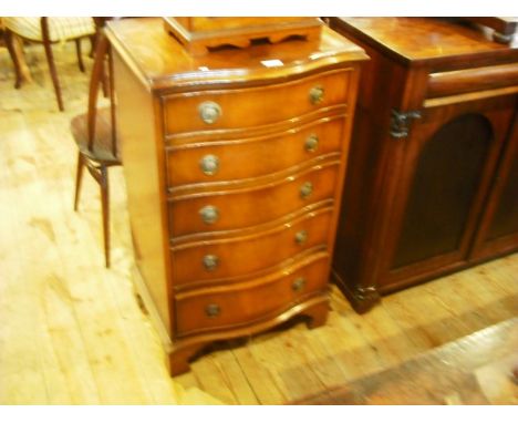 A reproduction mahogany veneered serpentine chest of five drawers on bracket feet.