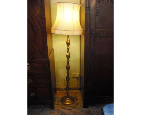 A brass standard lamp with cream shade.