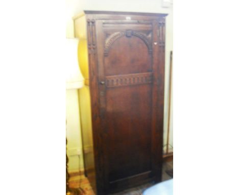 An oak single wardrobe, having moulded cornice over a panelled door enclosing single shelf and rail.