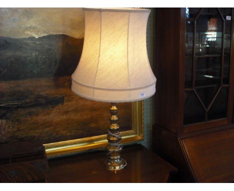 A brass table lamp, the turned knopped column supporting a cream shade.