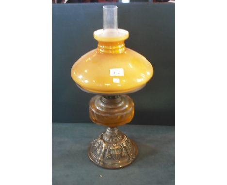 A late Victorian/Edwardian paraffin lamp, having clear chimney and caramel opaque glass shade, over clear glass reservoir on 