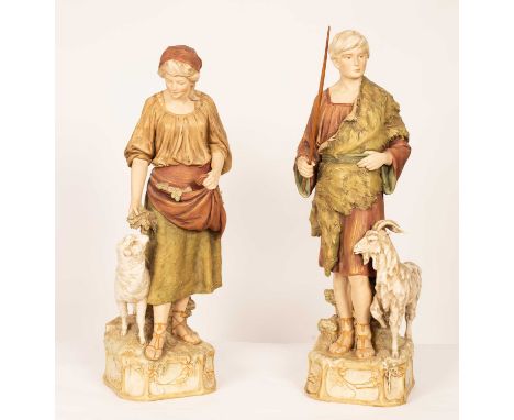 A pair of Royal Dux figures of a shepherd and shepherdess, each modelled standing, he with a goat, she with a lamb, 77.5cm hi