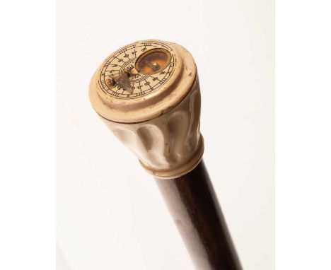 A rambler's walking stick with a grey bakelite knob handle fitted with a sundial and compass, the beech cane with a brass tip