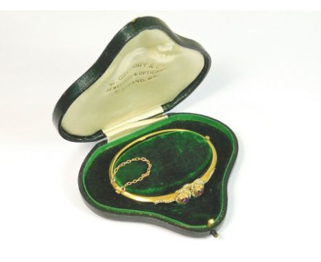 GOLD BANGLE. A Victorian, 15ct. gold bangle, the front set two heart shaped amethysts, between half pearl heart borders.