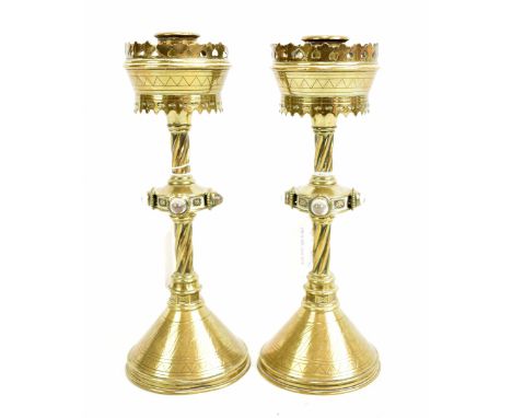 IN THE MANNER OF A W N PUGIN; a pair of brass Gothic Revival candlesticks, the knopped columns each set with four clear glass