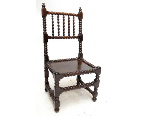 A 17th century bobbin-turned oak side chair with spindle set top rail above plank seat and ringturned and block front legs.