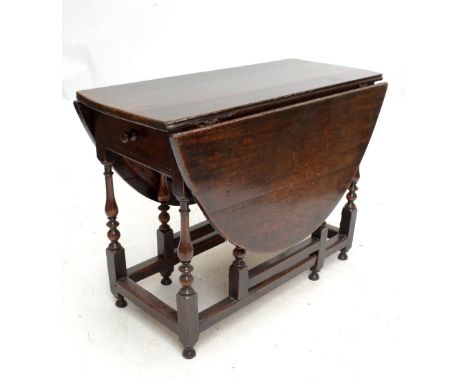 An 18th century oak gateleg dropleaf dining table raised on baluster ring turned block supports united by stretchers and with