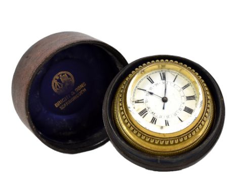 A brass cased circular travelling clock with enamel face set with Roman and Arabic numerals, in a Bright &amp; Sons Scarborou