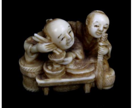 A Japanese Meiji period carved ivory netsuke of two figures eating, signed to base, length 4.2cm.