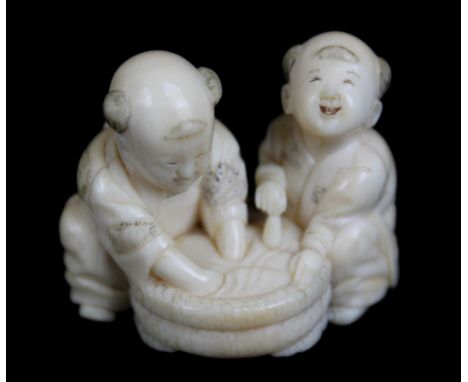 A Japanese Meiji period carved ivory netsuke of two figures washing, signed to base, length 4cm.