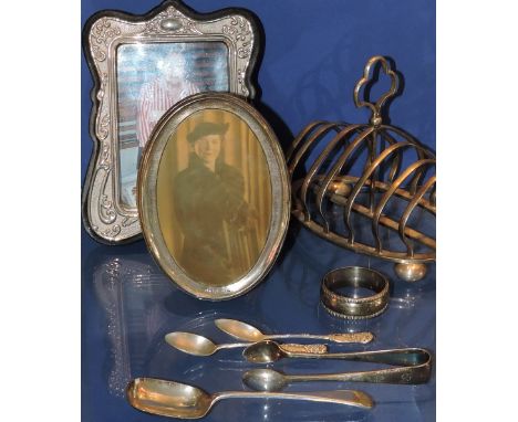 An oval silver photograph frame, a silver plater toast rack, a plated photograph frame, a plated napkin ring, three spoons an