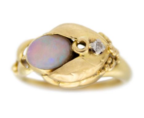 An 18k gold opal and diamond set dress ring. The oval white opal amongst leaves and berries, set with a tiny diamond, hallmar