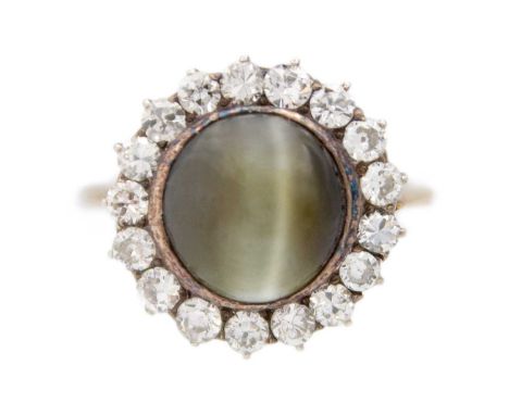 A late Victorian cat's eye chrysoberyl and diamond halo yellow gold ring. The rounded cabochon chrysoberyl is 9ct approx., di