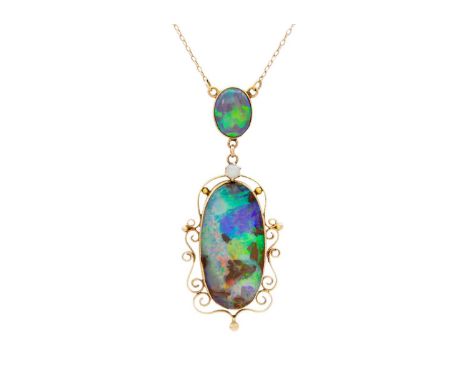 A good 9k gold black boulder opal pendant necklace. The elongated oval boulder opal is encased in a scroll frame with closed 