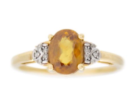 A 9k gold sphene (titanite) and diamond ring. The oval mixed-cut golden sphene is 8mm x 6mm, set with five round white melee 