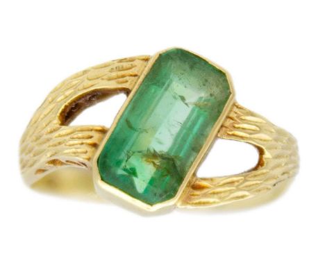 An emerald ring in 14k yellow gold. Rectangular shape, emerald-cut emerald, oil-treated, 10mm x 5.5mm, bezel set, with decora