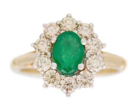 A 9k white and yellow gold oval emerald and diamond set cluster ring. The oval cut emerald of 0.85ct estimated weight, surrou