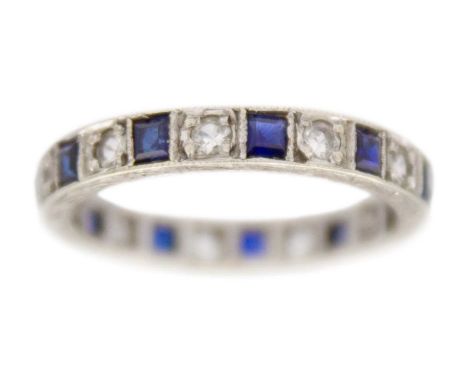 A 9k white gold synthetic sapphire and CZ eternity ring. Decorative engraving all around on a side of the ring, width 3mm, st