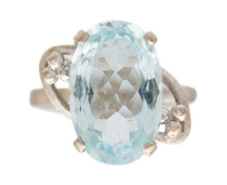 A platinum aquamarine set dress ring. The oval cut aquamarine of 4.15ct estimated weight, in a four claw openwork setting, si