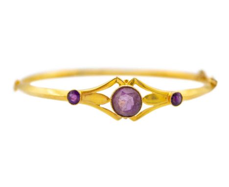An antique amethyst 9k yellow gold hollow bangle. The central round mixed-cut amethyst stone is 8mm in diameter, decorated by