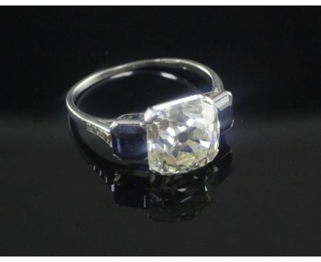 An impressive 1920's/1930's platinum and three stone diamond and sapphire ring, the central square cushion cut stone weighing