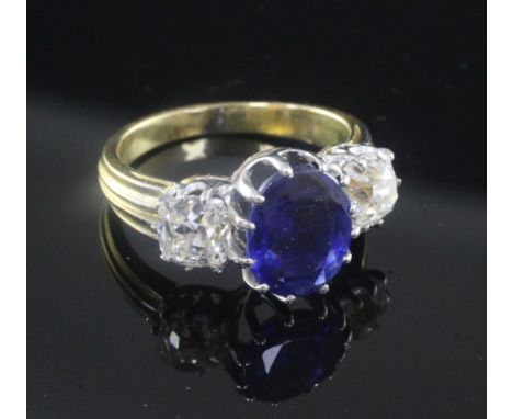 An 18ct gold and three stone sapphire and diamond ring, the central oval cut sapphire weighing in excess of 3.00cts and flank