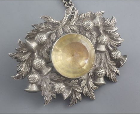 A 19th century Scottish white metal and citrine set cloak badge on chain, with thistle decoration, 9.5cm.
