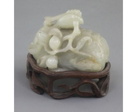 A Chinese celadon jade scroll weight, 17th / 18th century, carved as a recumbent phoenix grasping a peach branch, the stone w