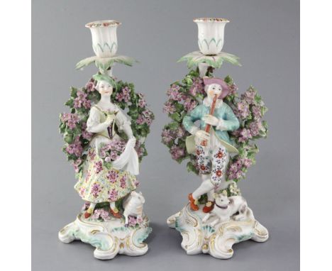 A pair of Derby candlestick figures, c.1770, modelled as a lady holding flowers in her apron and a gentleman playing a pipe, 