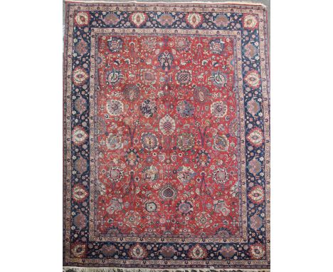 A Kirman red ground carpet, with field of scrolling foliage and five row border, 14ft 1in by 10ft 10in.