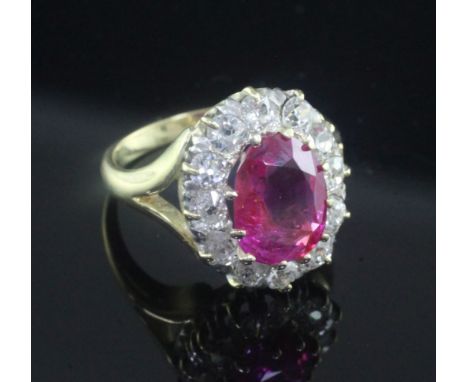 An 18ct gold, burmese ruby and diamond set oval cluster ring, the 3.30ct ruby with accompanying GCS certificate dated 31/01/2