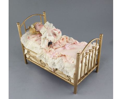 An early 20th century Austrian 'child in a bed' musical automaton, modelled with a girl sleeping in bed who sits up, kisses h