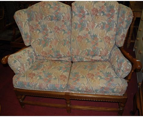 A contemporary Ercol mid elm three piece cloister suite comprising; two seater sofa and pair of armchairs, each with floral b