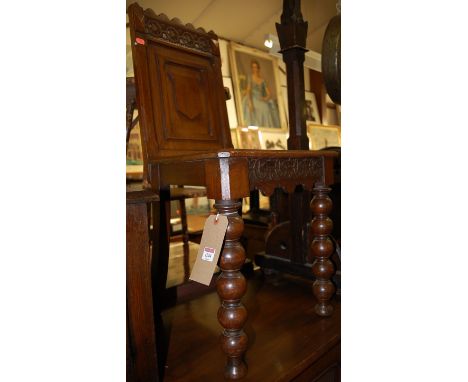 A Victorian low relief carved and panelled oak single hall chair, raised on bobbin turned forelegs