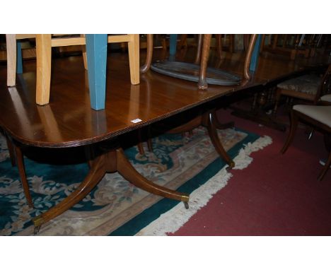 A 19th century mahogany round cornered twin pillar dining table, having a reeded edge, single extra drop-in leaf, and raised 