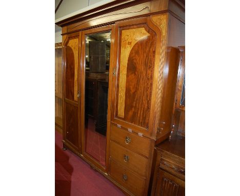 An Art Nouveau mahogany and floral satinwood inlaid triple wardrobe, comprising central bevelled mirrored door and twin panel