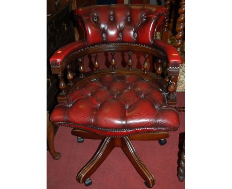 A reproduction mahogany and ox blood red leather button back upholstered swivel desk chair