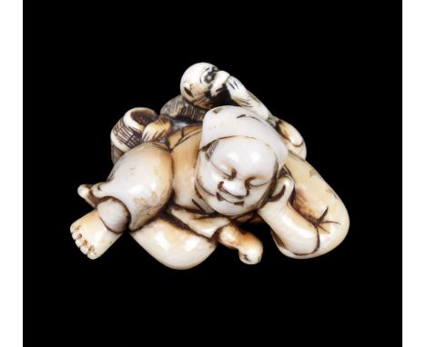 ϒ A Japanese carved Ivory Netsuke of a reclining sarumawashi dressed in typical garb and asleep on one elbow, his monkey stea