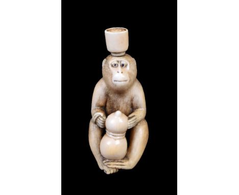 ϒ SHUGYOKU: A Japanese Ivory Netsuke carved as a monkey seated gripping a double-gourd between its legs and balancing a full 