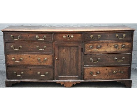 A George III oak low dresser, the rectangular top above three frieze drawers with six drawers below, flanking a central cupbo