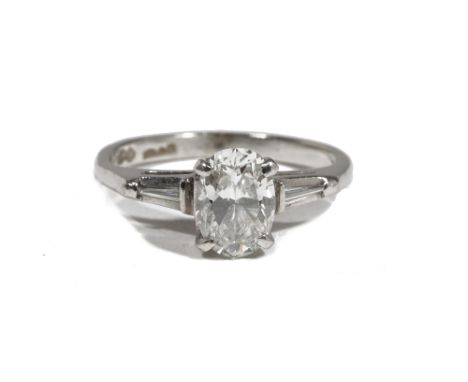 A platinum and diamond single-stone ring, the oval-cut diamond measuring 1.05ct approximately, claw-set with tapered baguette