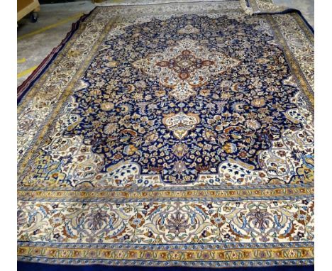 An Indian carpet, the indigo field filled with floral sprays, a central ivory border, matching spandrels; an ivory palmette a