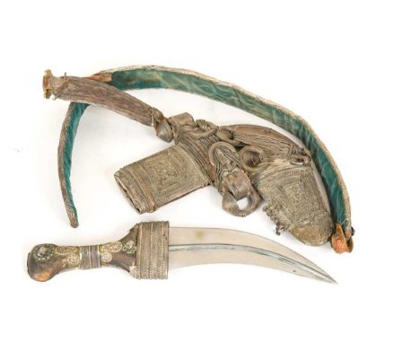 An Omani jambiya and belt, late 19th or early 20th century,  with horn handle, housed in an intricately decorated white metal