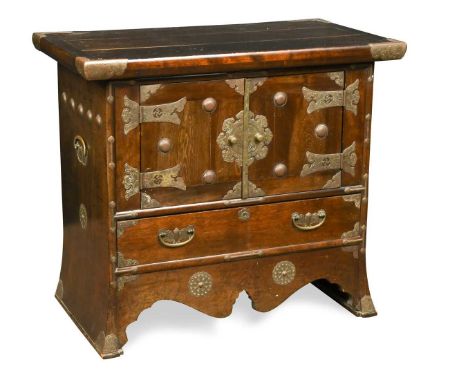 A Korean hard wood and metal mounted chest, 19th century, with metal doors enclosing a cupboard above a drawer with outswept 