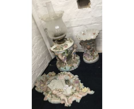 A Capodimonte oil lamp decorated with cherubs, together with a matching dish and bevelled glass mirror