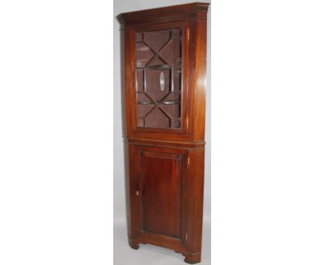 A George III style mahogany corner display cabinet, on stand, the upper section with an astragal glazed door revealing a shel