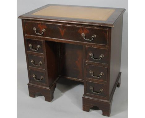 A Georgian style kneehole writing desk, the rectangular overhanging top set with a piece of stencilled brown leather above on